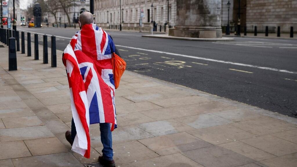 Un hombre con la bandera del Reino Unido camina por una calle solitaria de Londres, Inglaterra, el 31 de diciembre de 2020.