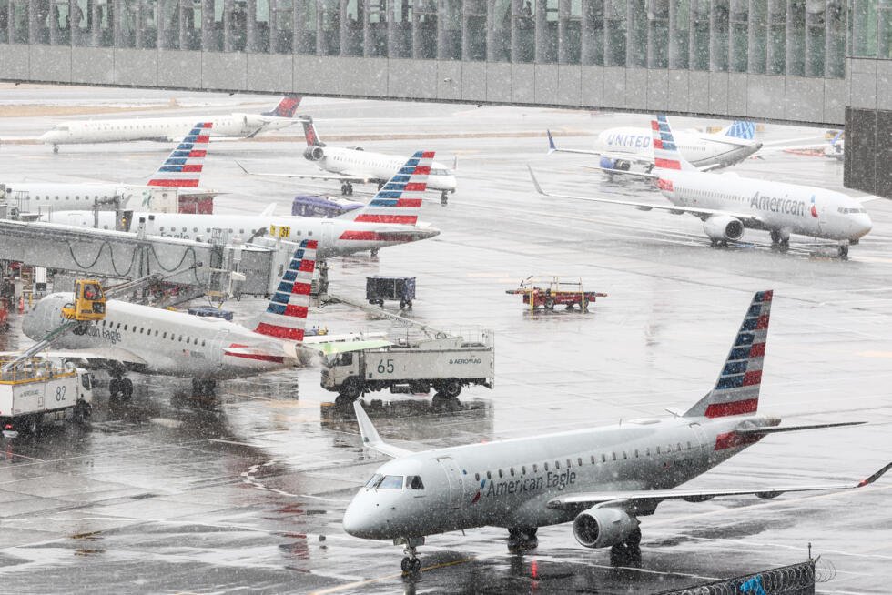 Un equipo de tierra descongela un avión de pasajeros Embraer ERJ-175 American Eagle (izq.) en el Aeropuerto LaGuardia en Nueva York el 22 de febrero de 2026.