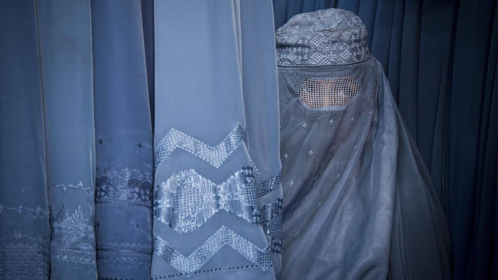 Sur cette photo datée du 11 avril 2023, une Afghane regarde à travers la fente de sa burqa alors qu'elle attend pour essayer une nouvelle burqa dans un magasin de la vieille ville de Kaboul.
