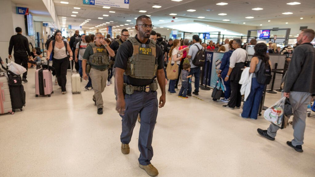 Agentes del Servicio de Inmigración y Control de Aduanas de Estados Unidos ( ICE ) patrullan mientras los pasajeros esperan en la fila en un puesto de control de la Administración de Seguridad del Transporte (TSA), luego de que cientos de agentes del ICE fueran desplegados en los aeropuertos para ayudar a cubrir las carencias de personal de la TSA, en el Aeropuerto Internacional Luis Muñoz Marín en Carolina, Puerto Rico, el 24 de marzo de 2026