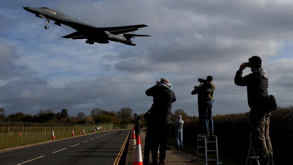 Varias personas toman sus cámaras mientras un bombardero B-1 de la USAF se aproxima para aterrizar en la base aérea RAF Fairford, utilizada por personal de la Fuerza Aérea de los Estados Unidos (USAF), en medio del conflicto entre Estados Unidos e Israel con Irán, en Fairford, Gloucestershire, Gran Bretaña, 17 de marzo de 2026.