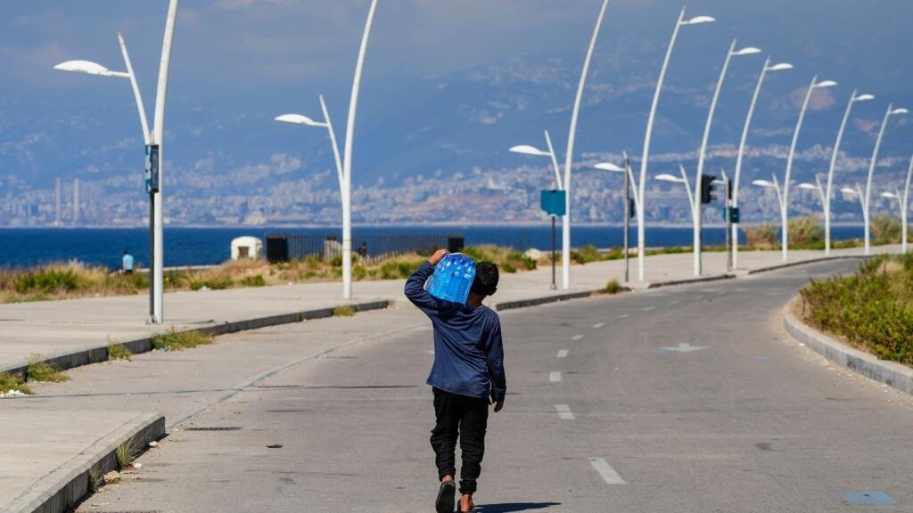 ARCHIVO - Un joven vendedor ambulante lleva un paquete de botellas de agua mientras busca clientes durante un día de calor sofocante en el paseo marítimo del mar Mediterráneo en Beirut, Líbano, el 20 de julio de 2023.
