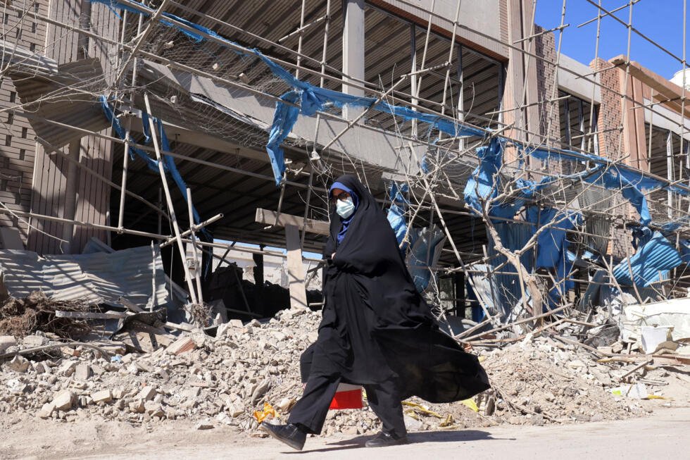Una mujer camina junto a un edificio muy dañado cerca de la plaza Ferdowsi en Teherán, el 3 de marzo de 2026.