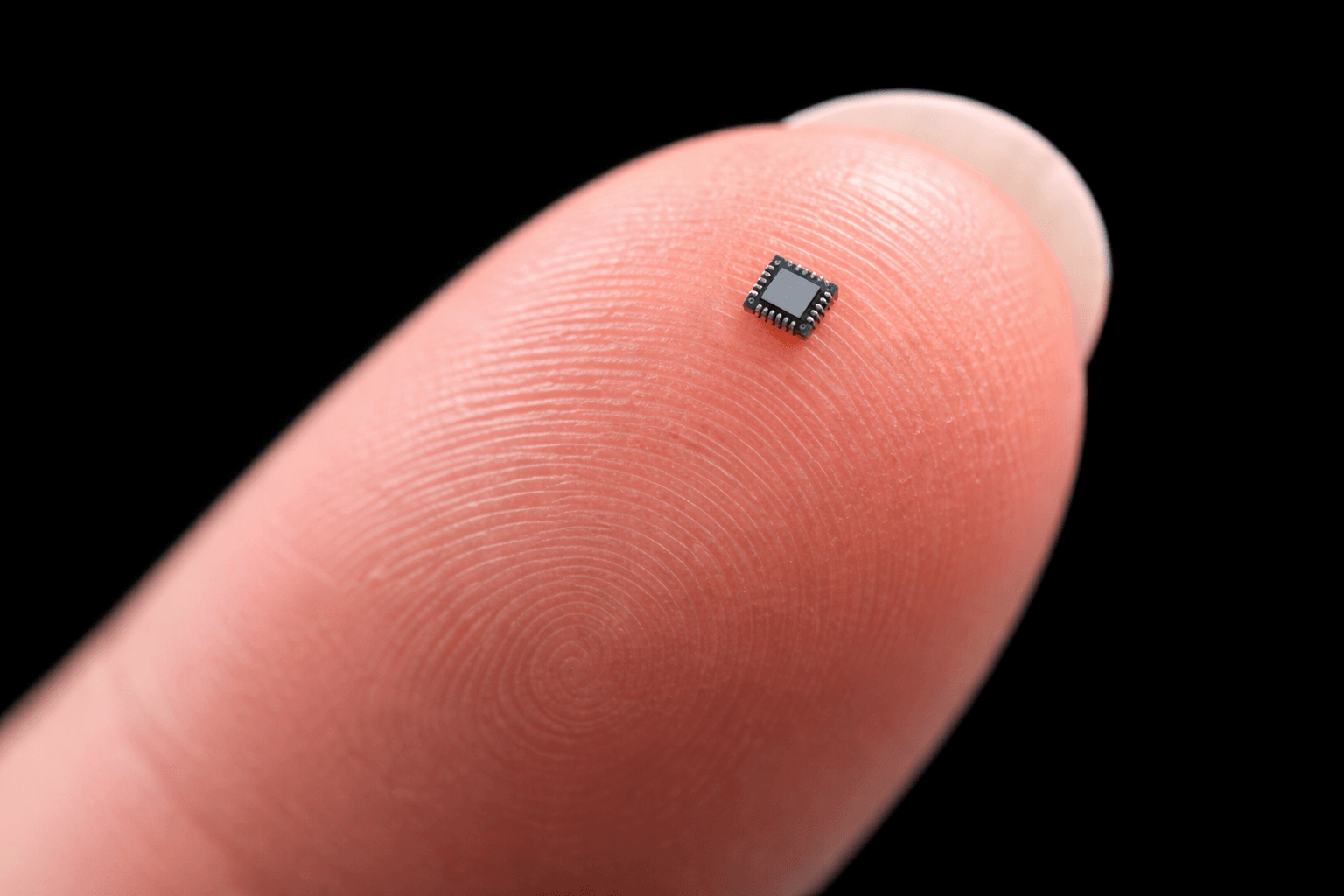 Un chip muy pequeño mostrado en la yema de un dedo para ilustrar su diminuta escala.