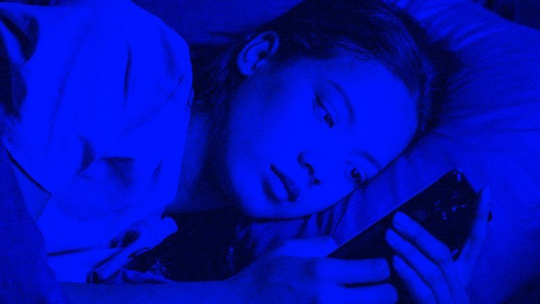 Mujer usando su teléfono en la cama por la noche