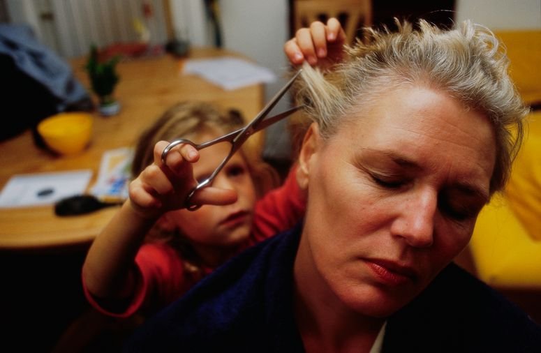Una niña corta el cabello de su madre antes de que se rasure en espera de quimioterapia por un caso de cáncer da mama.