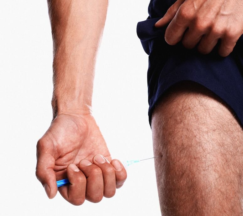 Persona deportista inyectándose testosterona. 