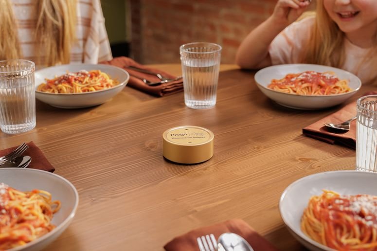 Una familia reunida alrededor de la mesa comiendo pasta. El dipositivo de Prego en medio. 