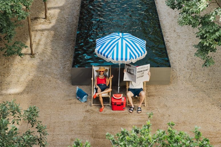 dos personas sentadas en sillas de playa frente a una piscina